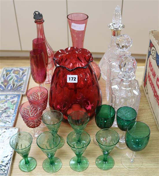 A cranberry glass, silver collared decanter and green glass ware